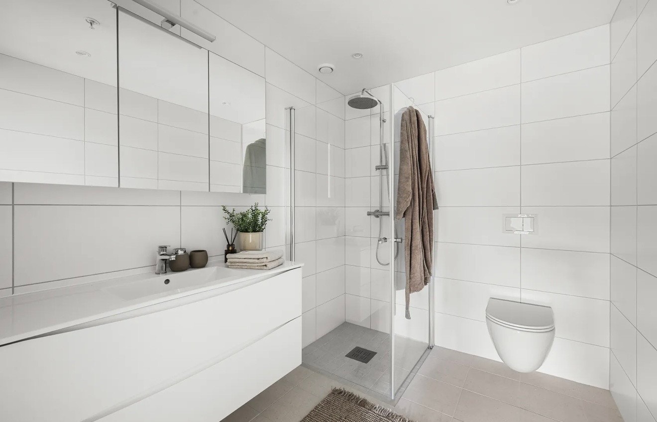 Stilrent helfliset baderom med gulvvarme. Badet er utstyrt med vegghengt toalett og dusjhjørne med innfellbare glassvegger Galleribilde