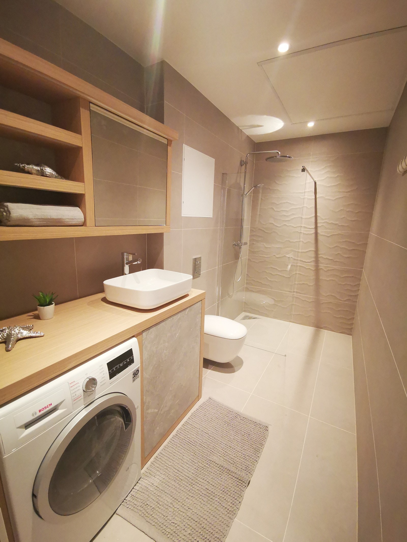 Badet er holdt i behagelige farger, og har prkatisk innredning samt fliser på gulv og vegger Galleribilde