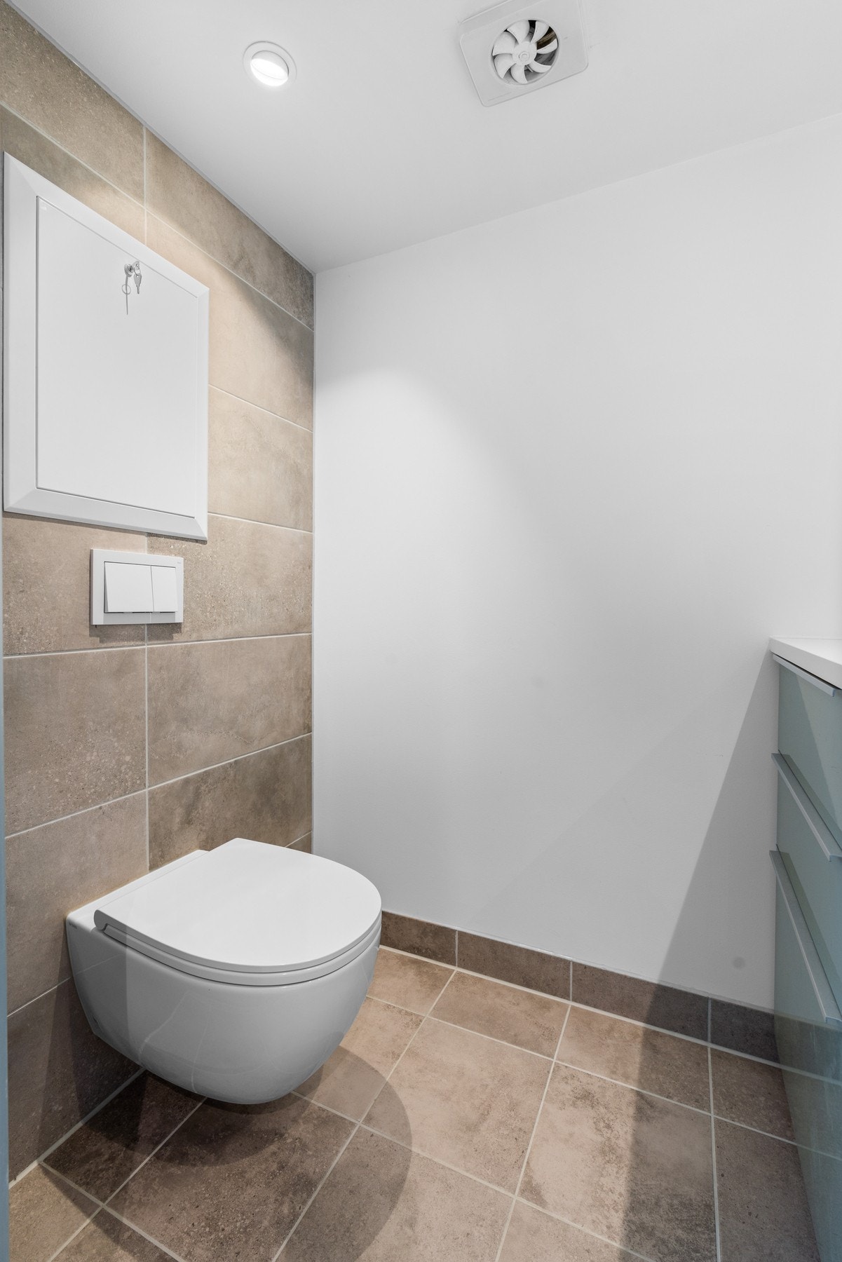 Badet har delikate fliser på gulv og de fleste vegger, og et vegghengt toalett Galleribilde