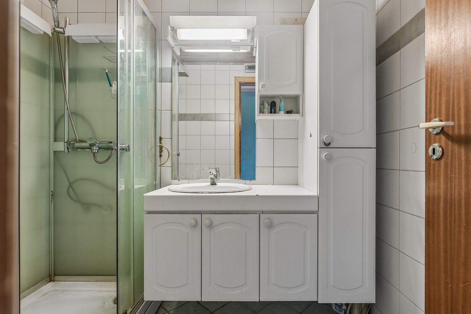 Badet er flislagt og utstyrt med servantinnredning, høyskap og dusjkabinett. Galleribilde