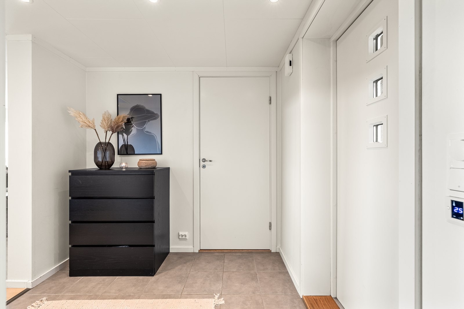 Lys entre ønsker velkommen inn. Her er det fliser med varme i gulvet og det plass til oppbevaring av yttertøy i skuffer. Galleribilde