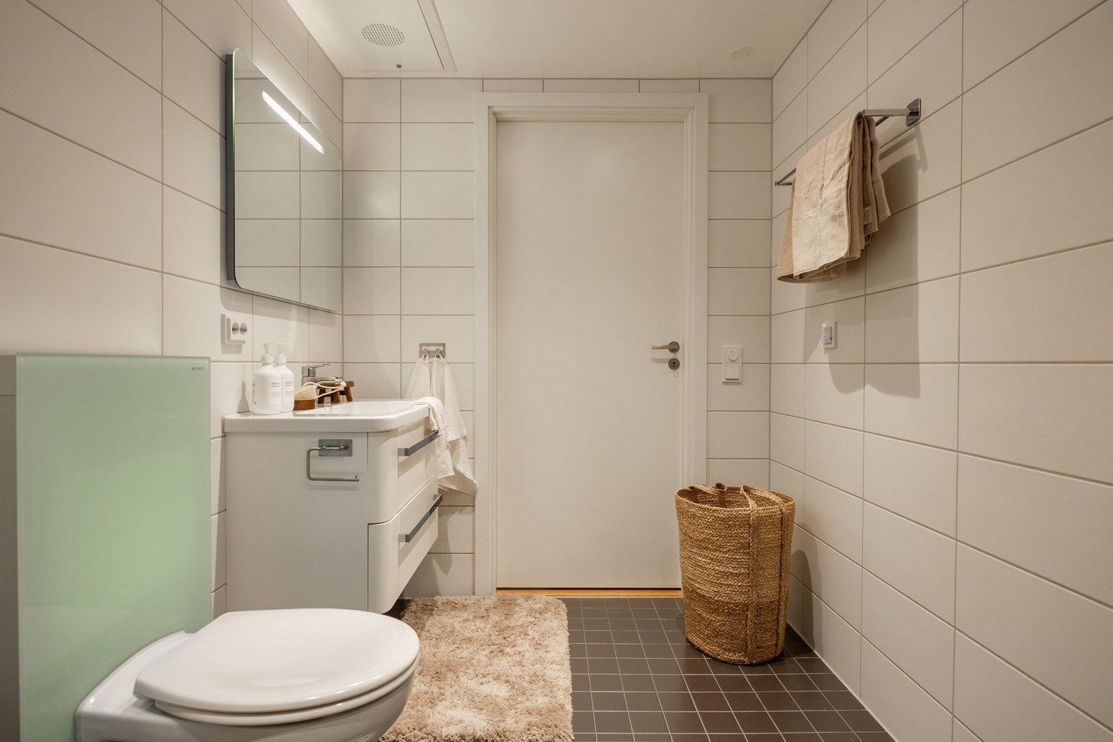 Badet er innredet med stilrene skap med glatte fronter og speil over servant. Galleribilde