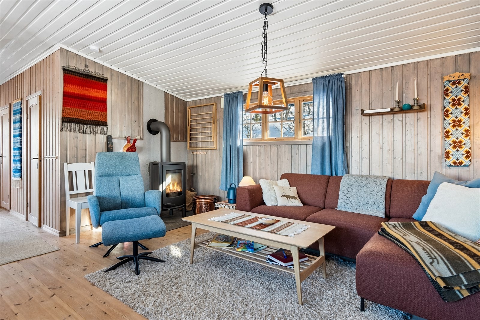 Her er det fin plass til både sofa- og spisegruppe, og en stilig, rentbrennende peisovn med innsyn gir god varme til rommet. Galleribilde
