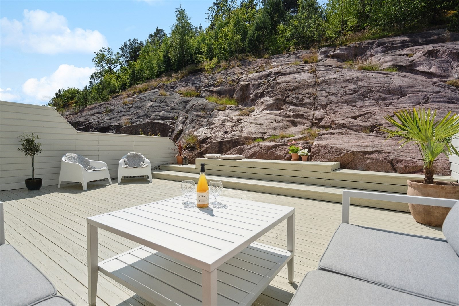 Terrassen er bygget i flere nivåer og rammes inn av en naturlig fjellvegg som skaper en lun og privat uteplass. Galleribilde