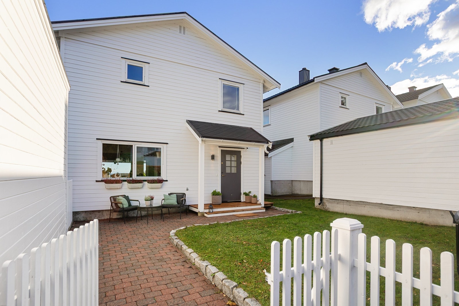 Pent opparbeidet uteområde med belegningsstein, gjerde og plen Galleribilde
