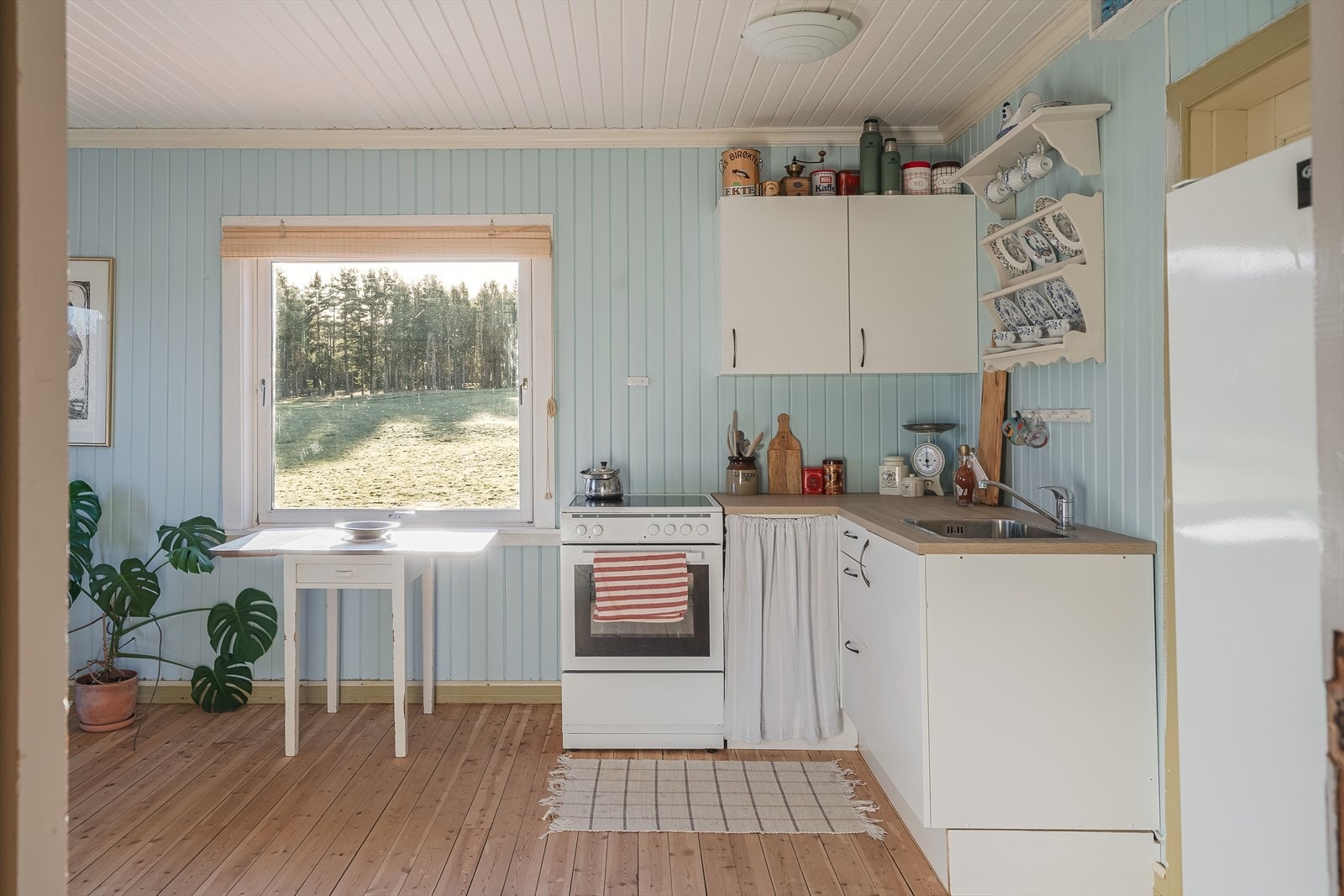 Nyere kjøkkeninnredning fra 2022 med hvite glatte fronter og laminert benkeplate med nedfelt oppvaskkum. Galleribilde