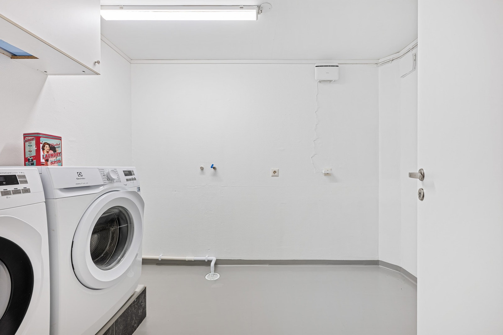Vaskerommet har nymalte vegger og malt laminat som er lagt oppå betonggulv. Her ligger alt til rette for å lage til et praktisk vaskerom med oppbevaringsplass .Opplegg for vaskemaskin og plass til tørketrommel. Galleribilde