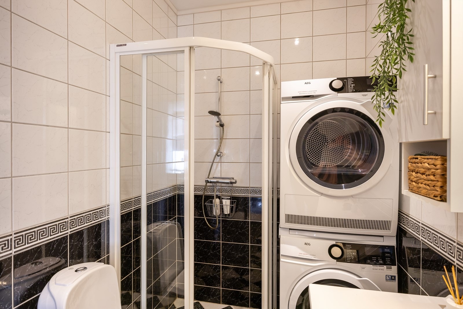 Badet er utstyrt med dusjvegger i glass, WC, Innredning med servant og opplegg for vaskemaskin. Vaskemaskinen og tørketrommelen medfølger handelen. Galleribilde