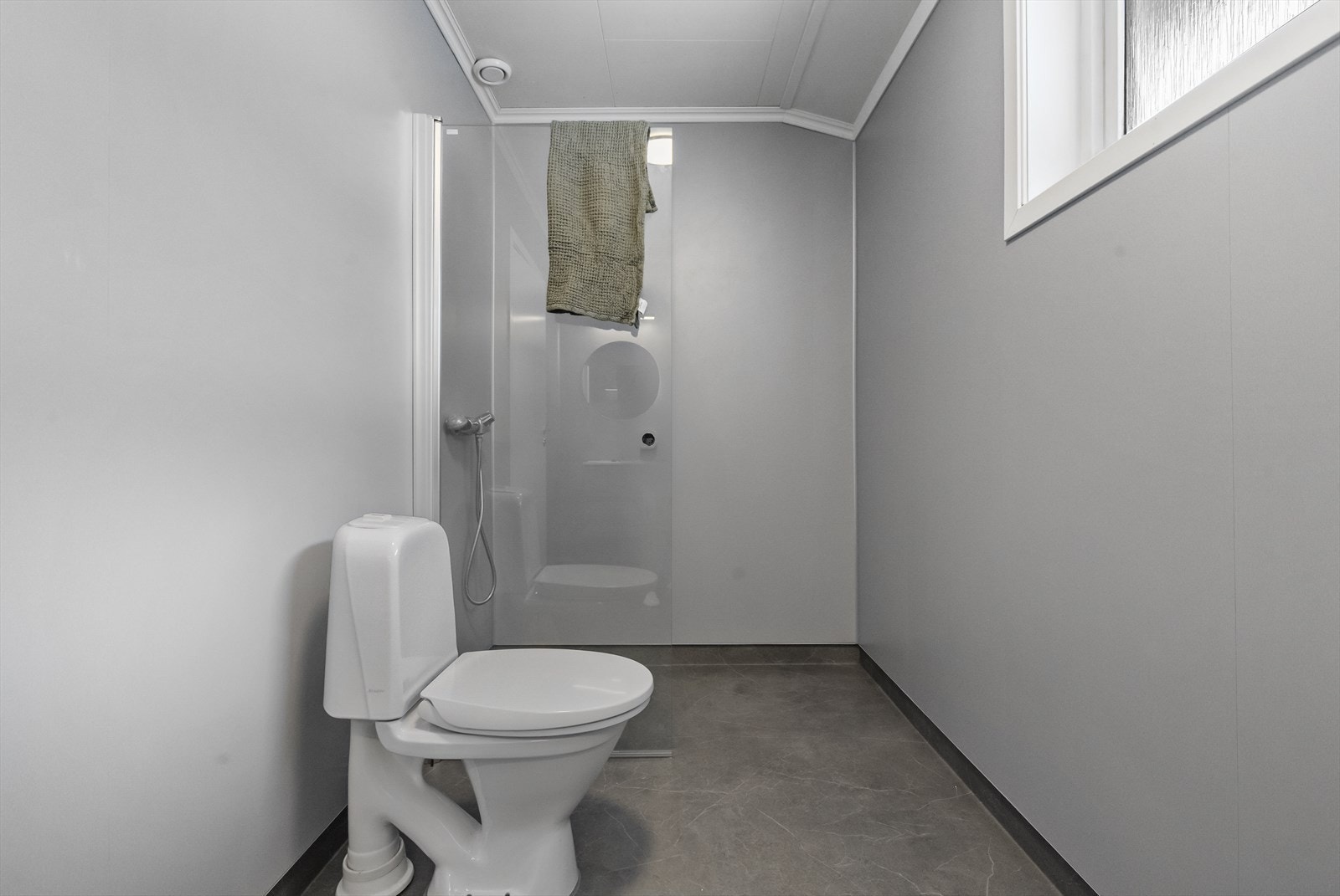 Badet er utstyrt med veggmontert dusj med glasvegg, klosett og servantskap. Galleribilde