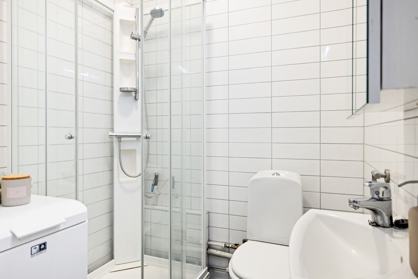 Bad med servantinnredning, speil, opplegg for vaskemaskin og flislagte overflater Galleribilde