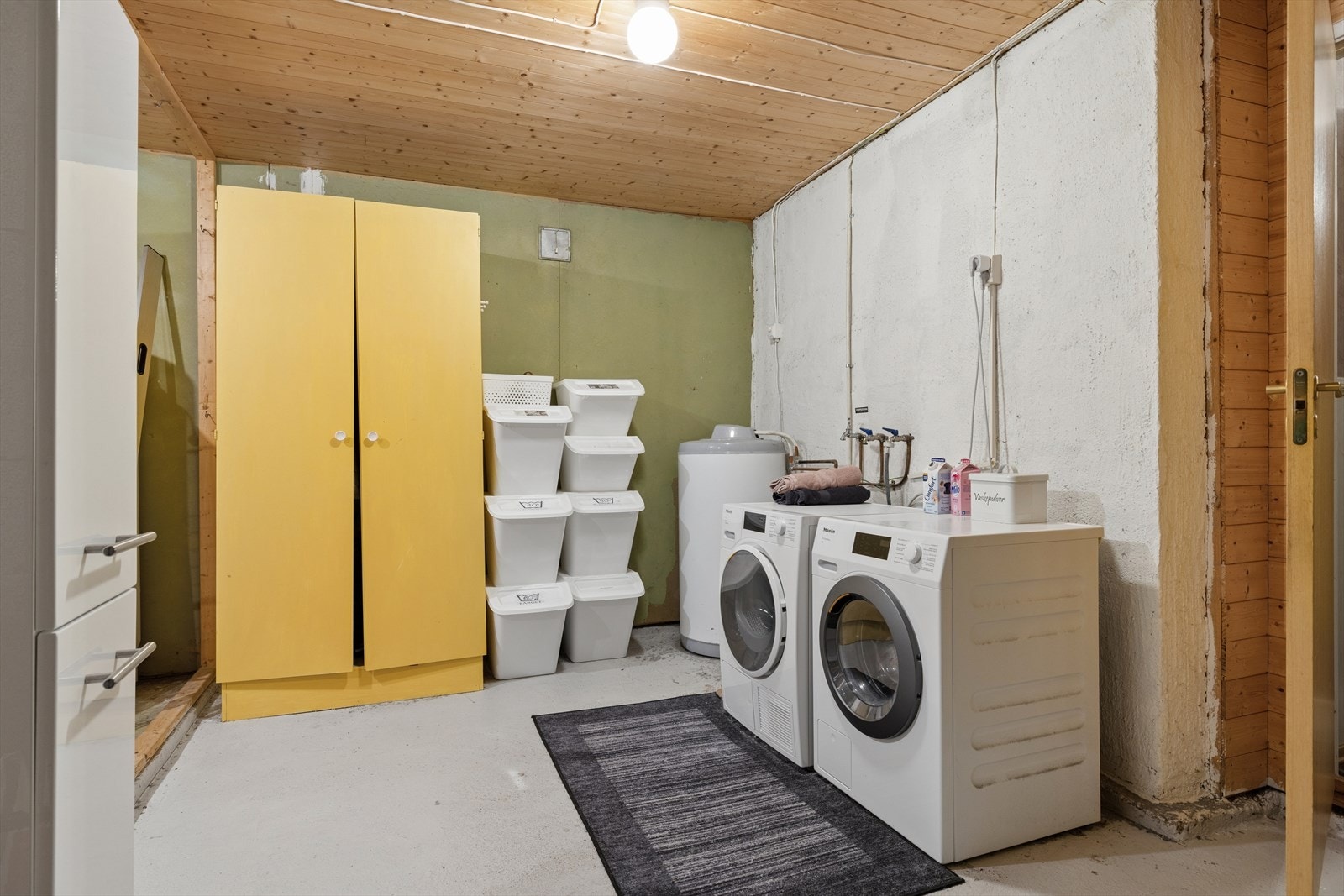 Stort teknisk rom med opplegg for vaskemaskin, sluk i gulv og en 200-liters varmtvannsbereder. Her er også boligens radonsug plassert. Galleribilde