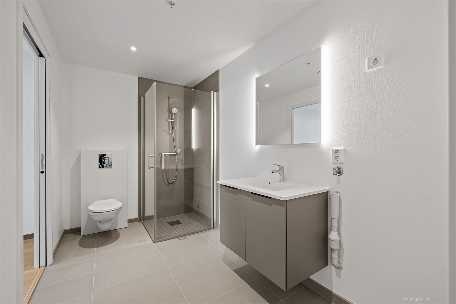 Badet er et kombinert bad og vaskerom og er delikat innredet med lyse overflater og downlights i himling. Galleribilde