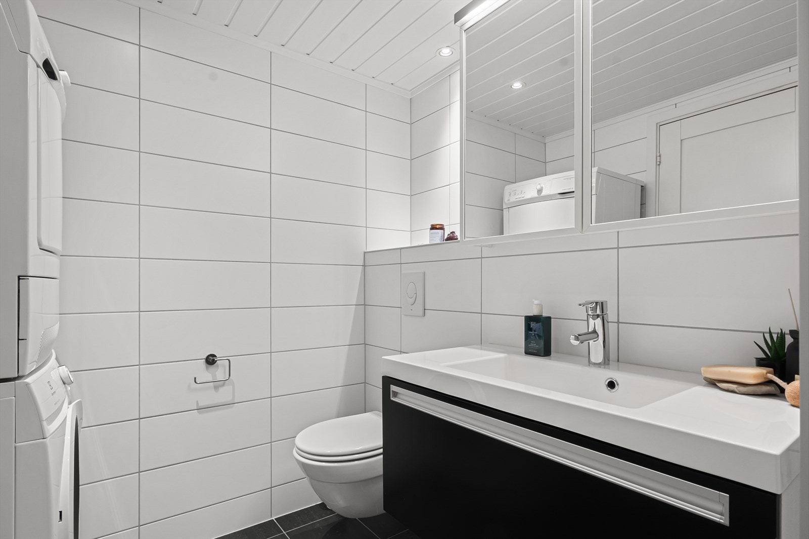 Badet har flislagte overflater, gulvvarme, downlights og røropplegg for vaskemaskin med plass til vaskesøyle. Galleribilde