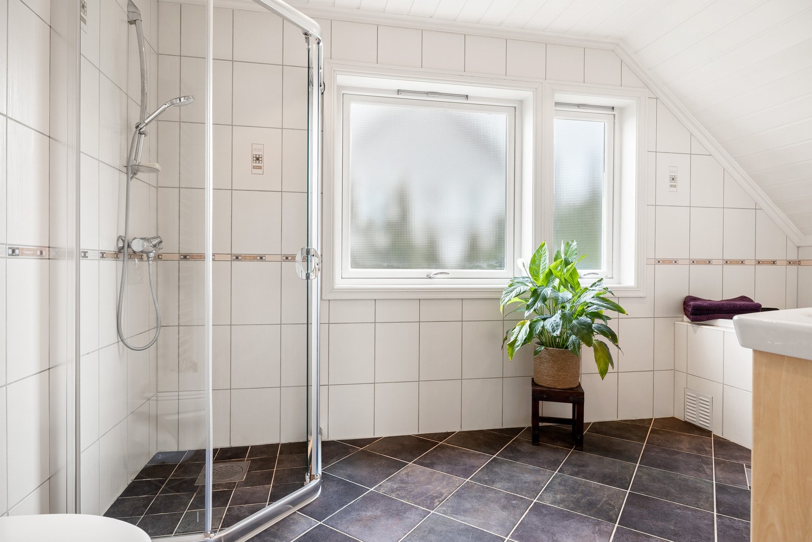 Bad med lysinnslipp, dusjhjørne og vegghengt toalett. Galleribilde