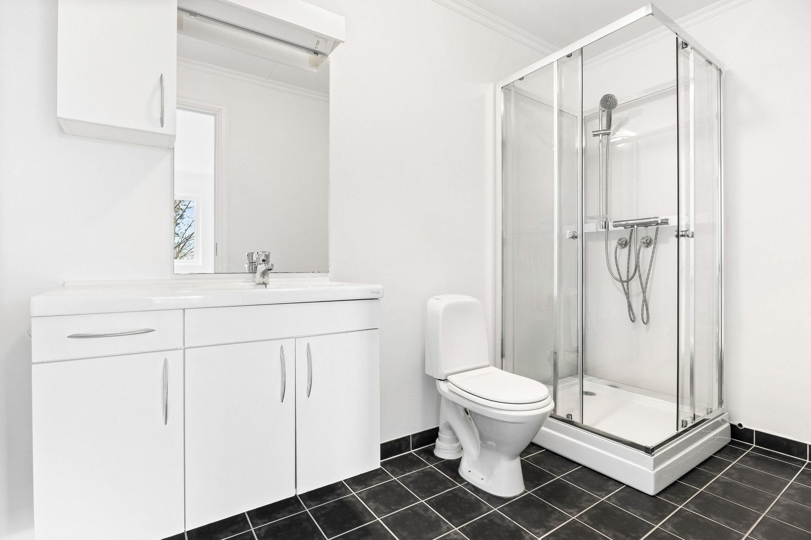 Badet i sokkelleiligheten har flislagt gulv med elektrisk varme, servant integrert i skapinnredning, speilskap og lys. Nytt dusjkabinett (april -26). Wc og opplegg for vaskemaskin og tørketrommel. Galleribilde