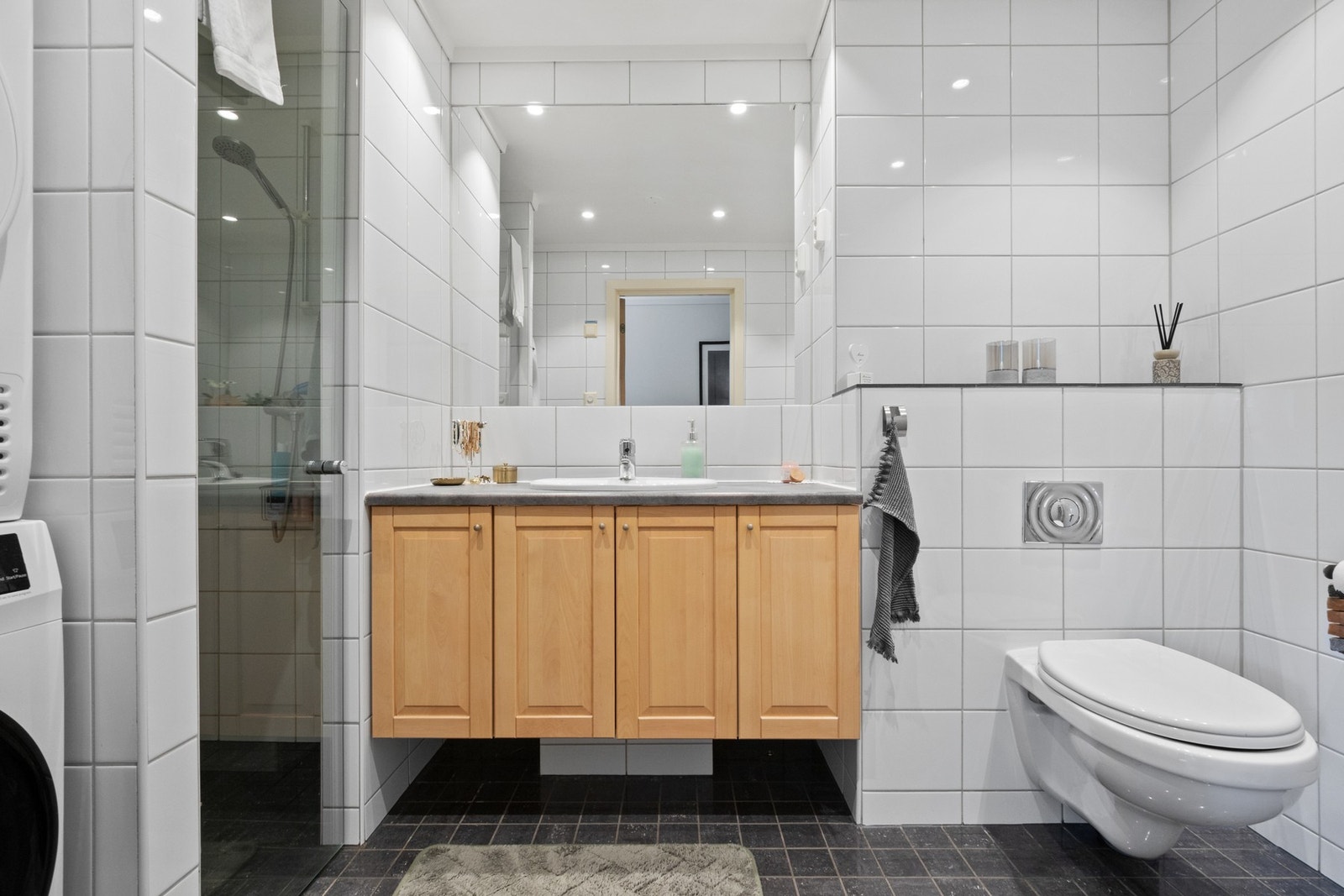 Badet er fra byggeår og inneholder dusj, innredning med nedfelt servant, vegghengt toalett og opplegg for vaskemaskin. Galleribilde