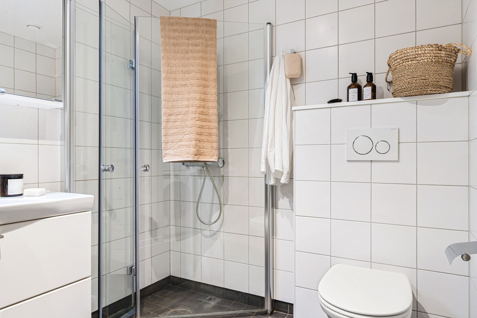 Badet er innredet med dusj med glassvegger, vegghengt toalett, baderomsinnredning og opplegg for vaskemaskin. Galleribilde