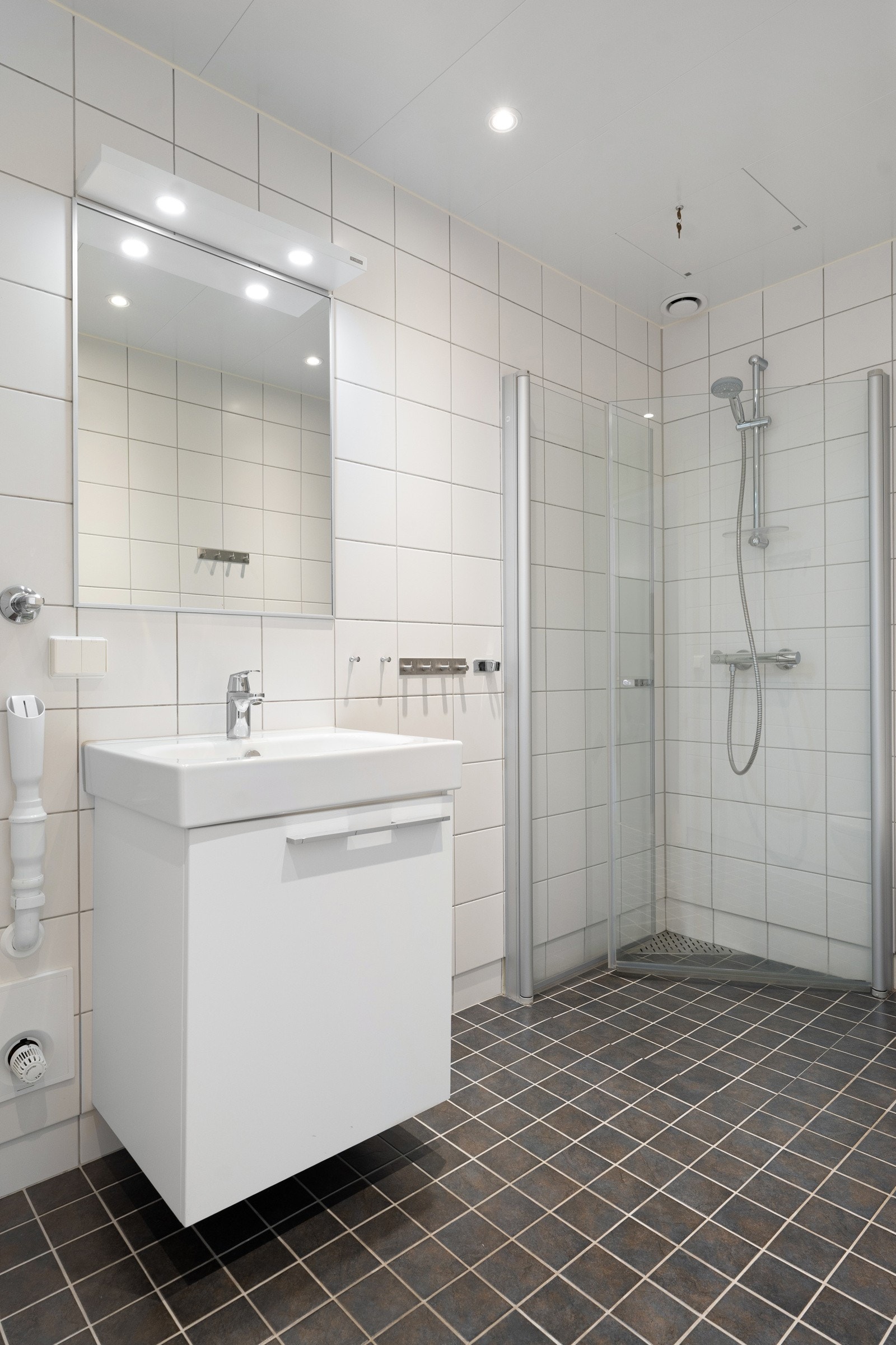 Av utstyr finnes innredning med servant, dusjvegger av glass og dusjgarnityr på vegg, samt opplegg for vaskemaskin.