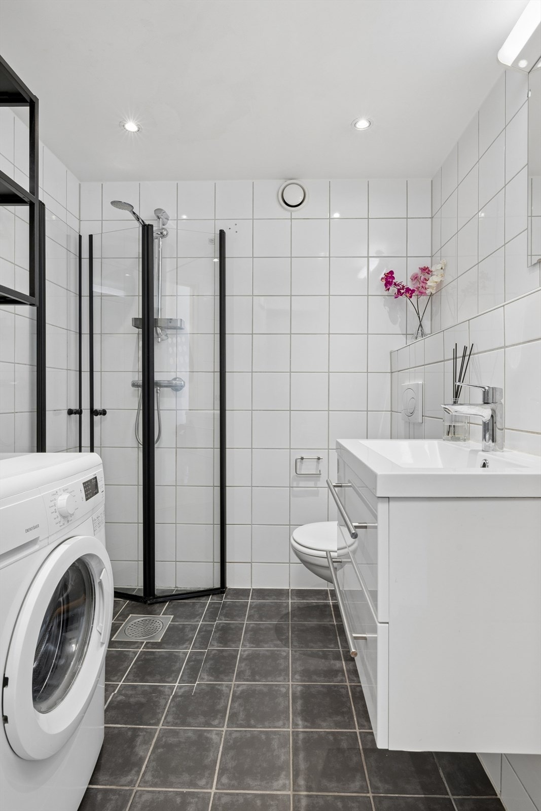 Rommet har innredning med servant, speil, belysning, veggmontert toalett, innfeltbare dusjvegger/hjørne i herdet glass og opplegg for vaskemaskin. Galleribilde