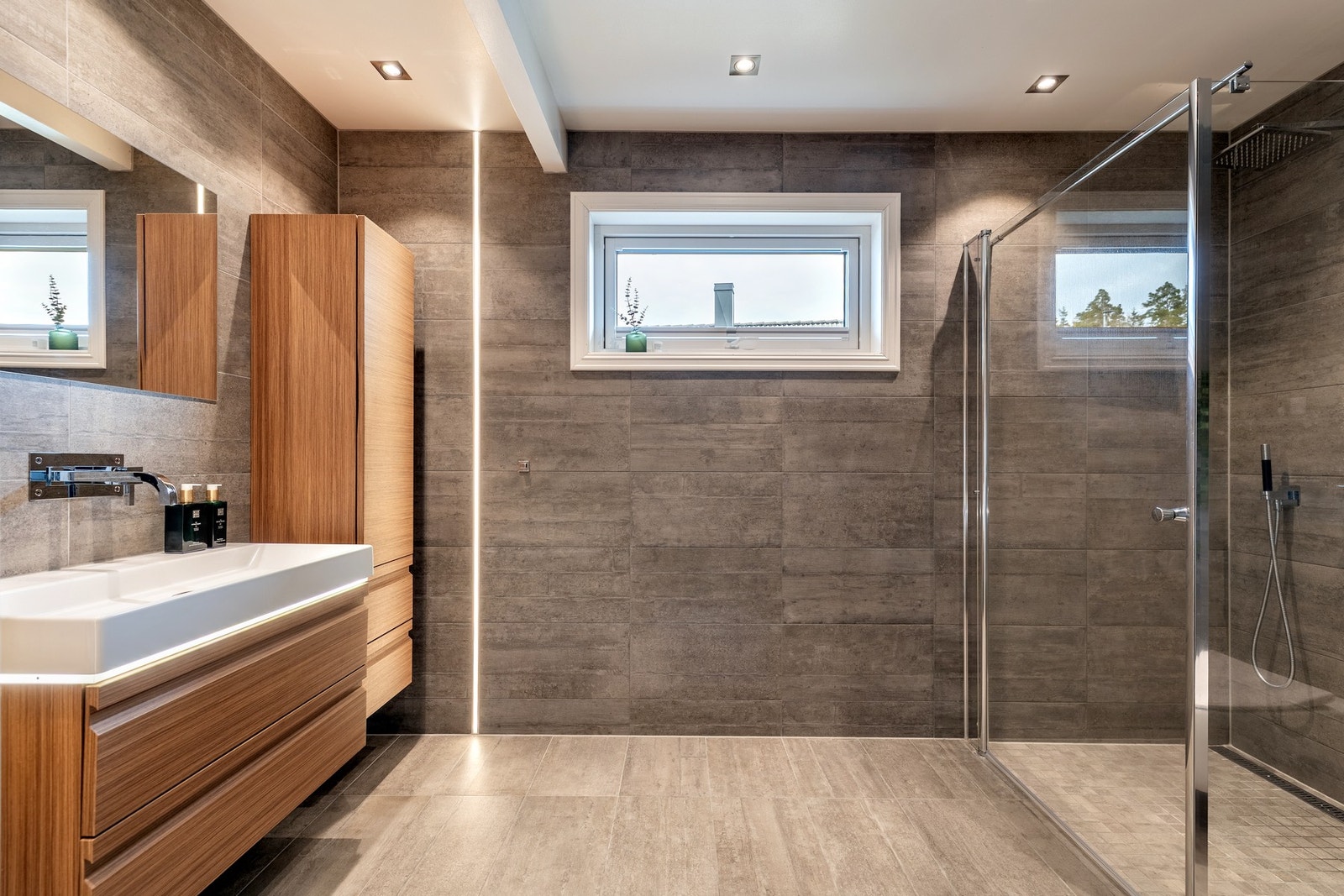 Badet ble pusset opp i 2016 og har et stilfullt utrykk med store vegg- og gulvfliser i grå toner, innfelt downlights og varmekabler. Galleribilde