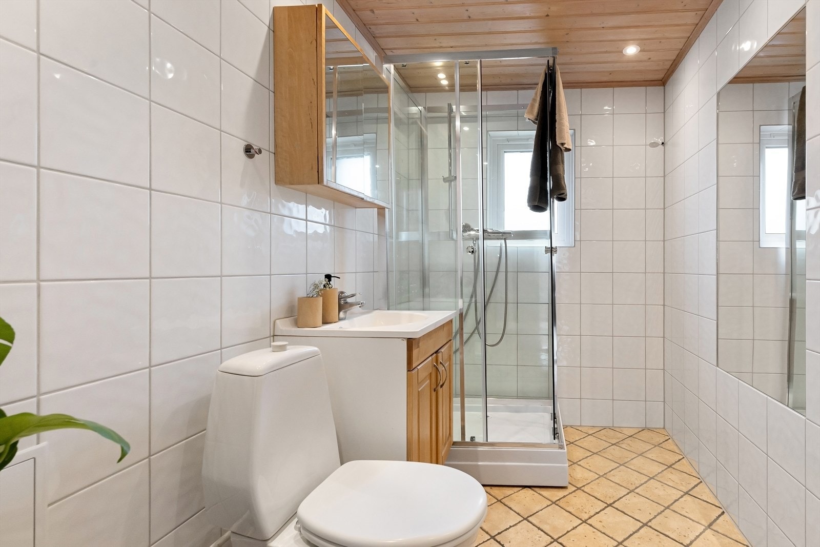 Eldre, flislagt bad med downlights i himling, innmurt speil, dusj, speilskap, servantinnredning og toalett. Galleribilde