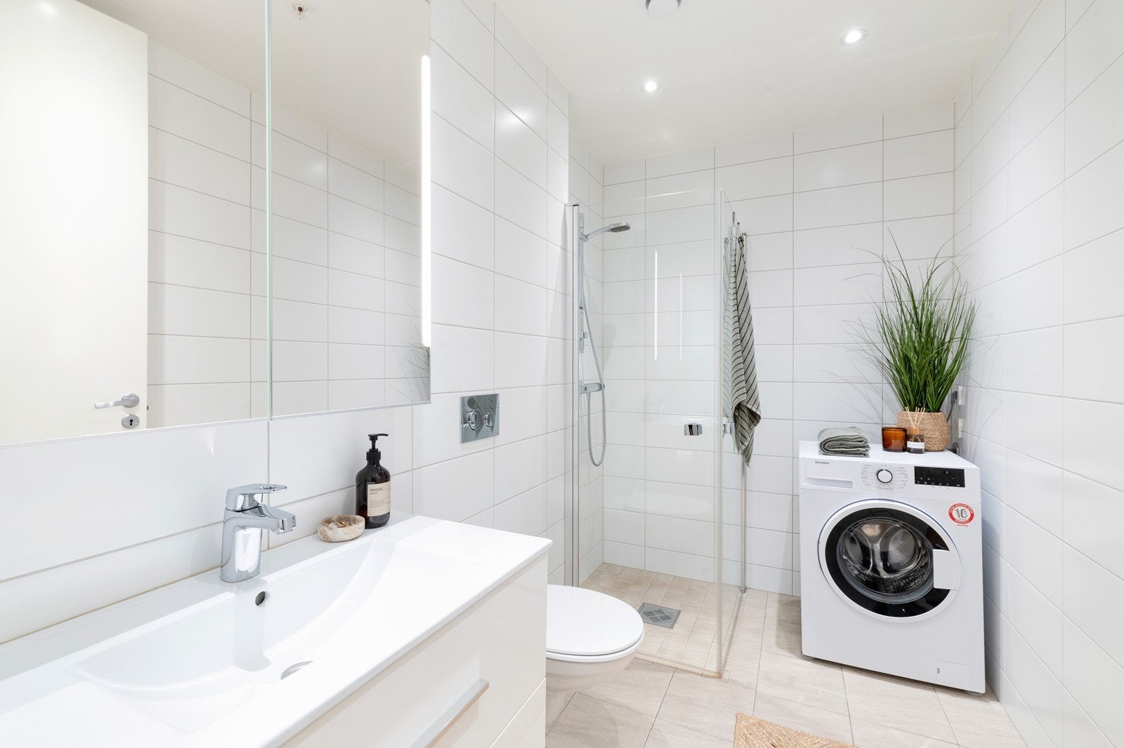 Badet er flislagt med servant, dusjhjørne og toalett. Baderommet er romslig med moderne valg. Det er opplegg for vaskemaskin på baderom. Galleribilde