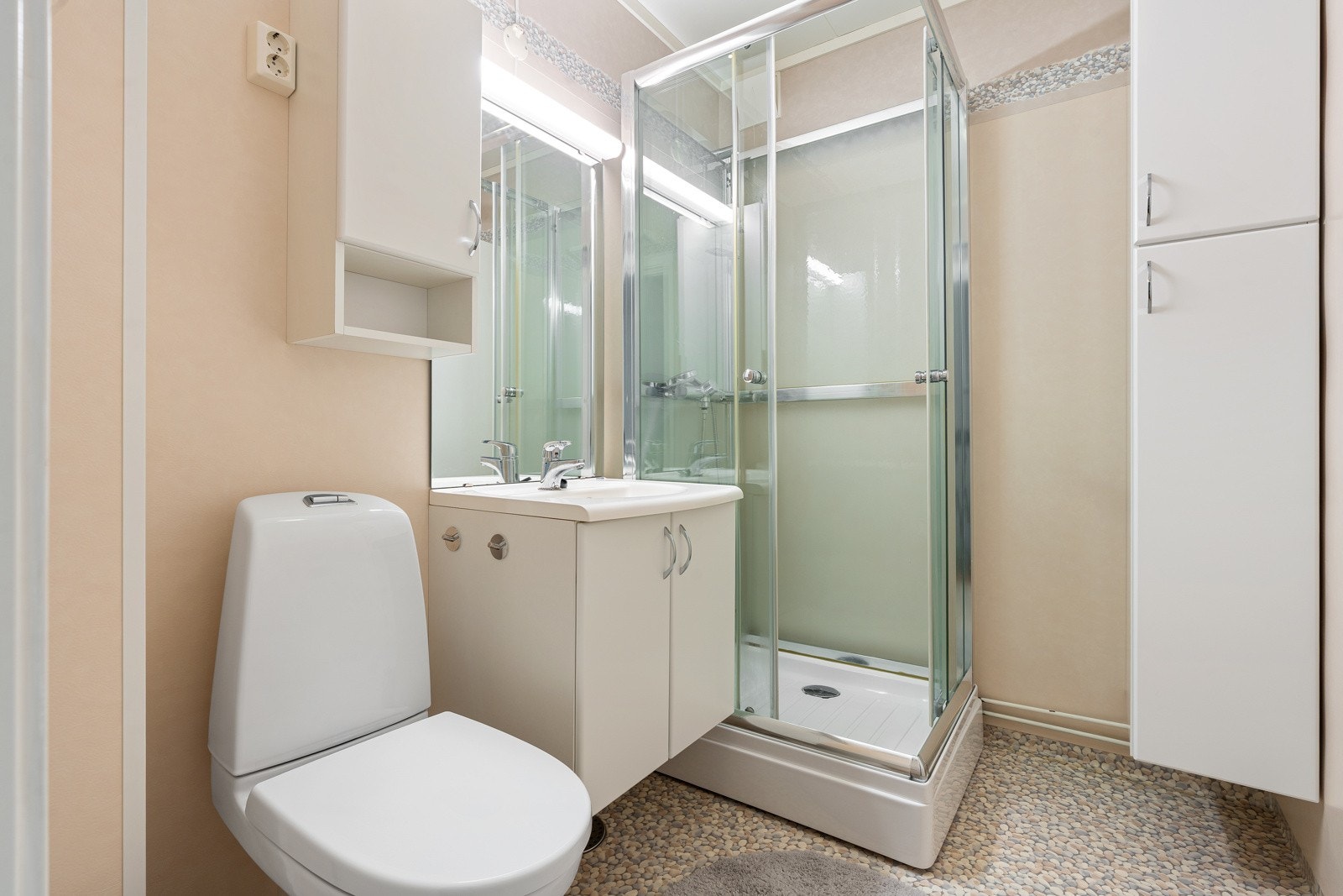 Baderom med dusjkabinett og ekstra lagrinsplass i høyskap.