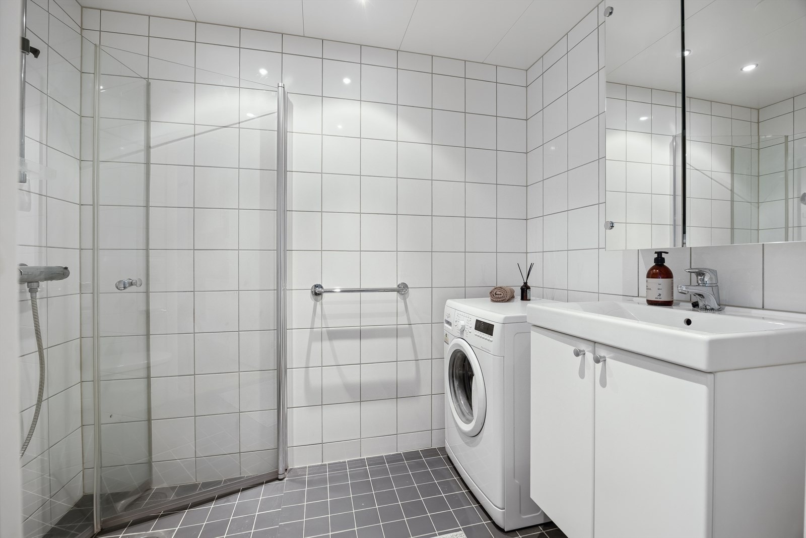 Utleiedelens bad har samme tidløse flisvalg som hovedbadet. Begge bad har opplegg for vaskemaskin. Galleribilde