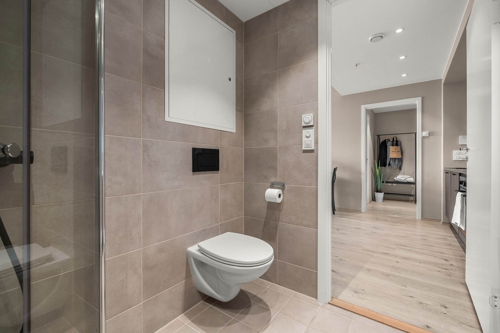 Badet er utstyrt med vegghengt toalett, dusjvegger i glass og servantinnredning. Galleribilde
