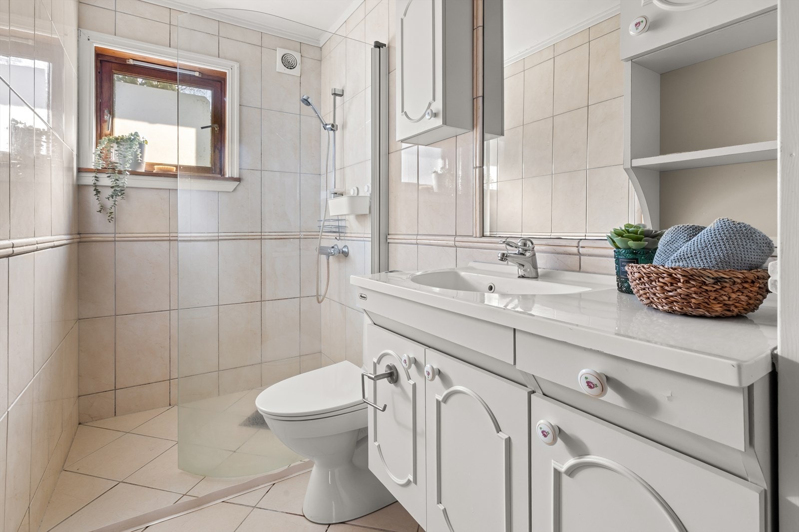 Vi fortsetter videre til badet, som fremstår moderne med flislagte overflater og et stilrent preg. Galleribilde