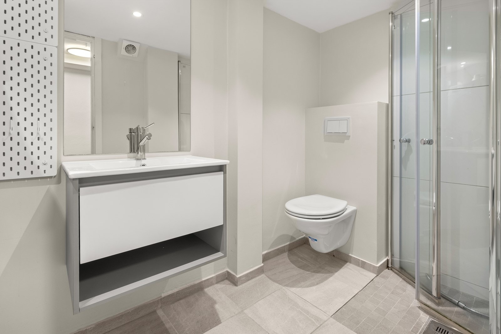 Videre beveger vi oss inn på badet, som fremstår moderne med flislagte overflater og et stilrent uttrykk. Galleribilde