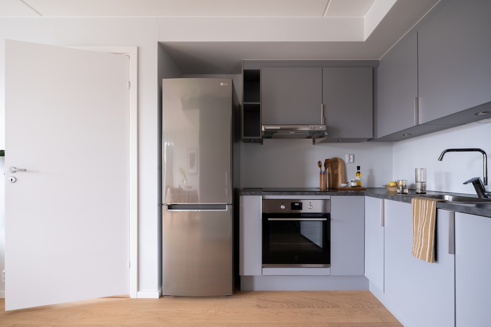 Grå, glatt innredning med laminat benkeplate og kum i rustfritt stål med ett-greps armatur. Galleribilde