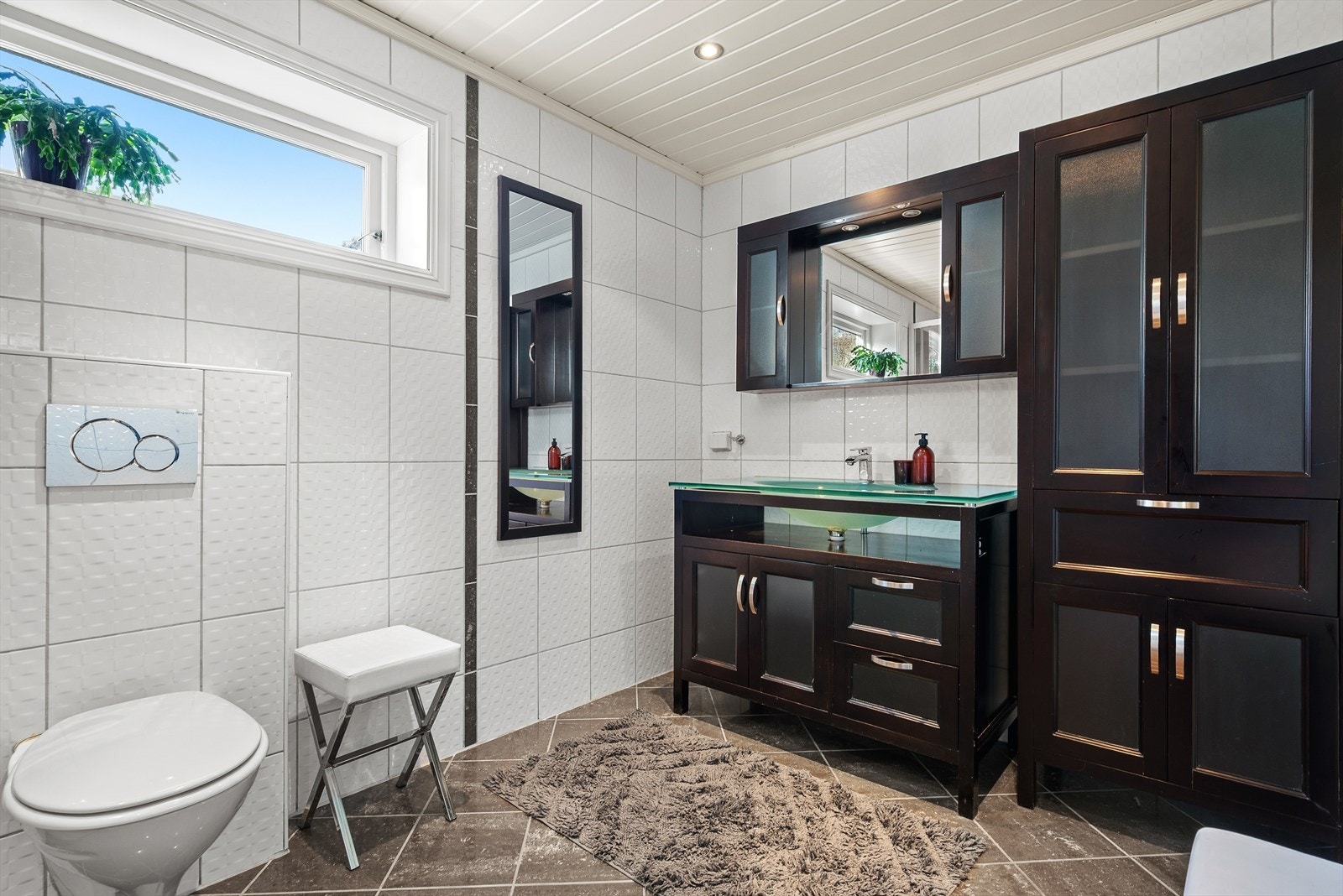 Badet har en moderne innredning og utstyrt med flis på gulv og vegger. Galleribilde