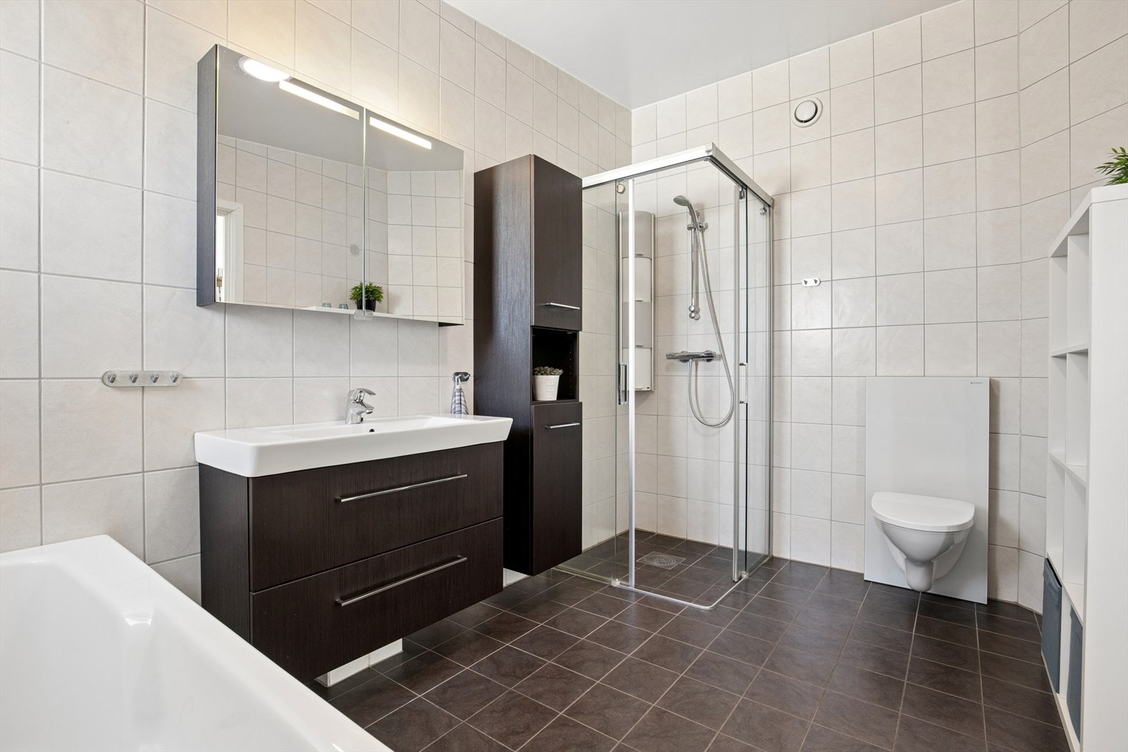 Hovedbadet i andre etasje fremstår som romslig. Gulvet og veggene er flislagte og gir et moderne uttrykk. Badet er utstyrt med både badekar og et separat dusjhjørne med glassvegger. Galleribilde