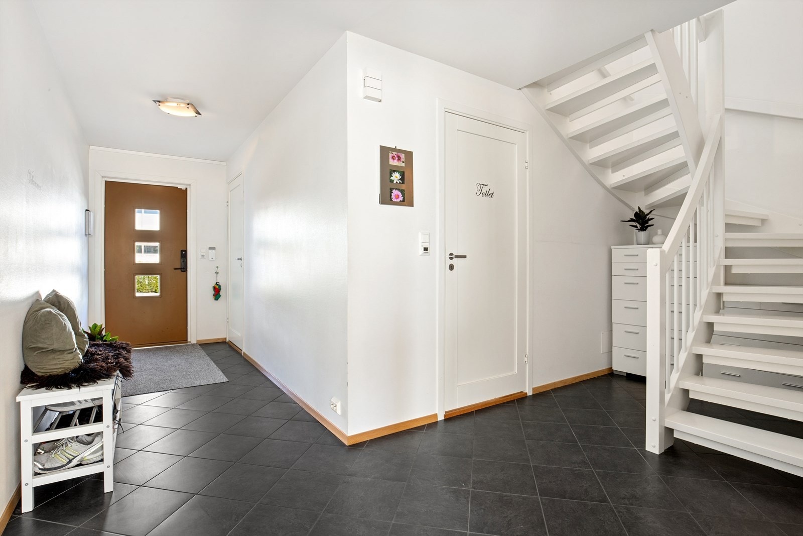 En romslig entré med flislagt gulv ønsker velkommen inn. Galleribilde