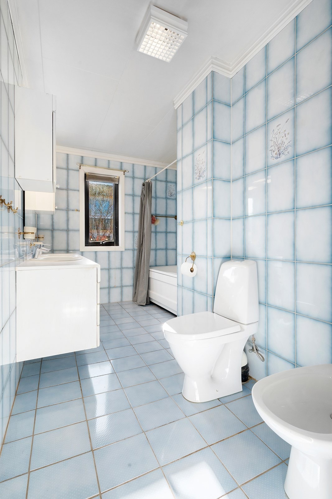 Badet har gulv med fliser og gulvvarme. Montert skapinnredning med to servanter, badekar, gulvmontert klosett og bide. Galleribilde
