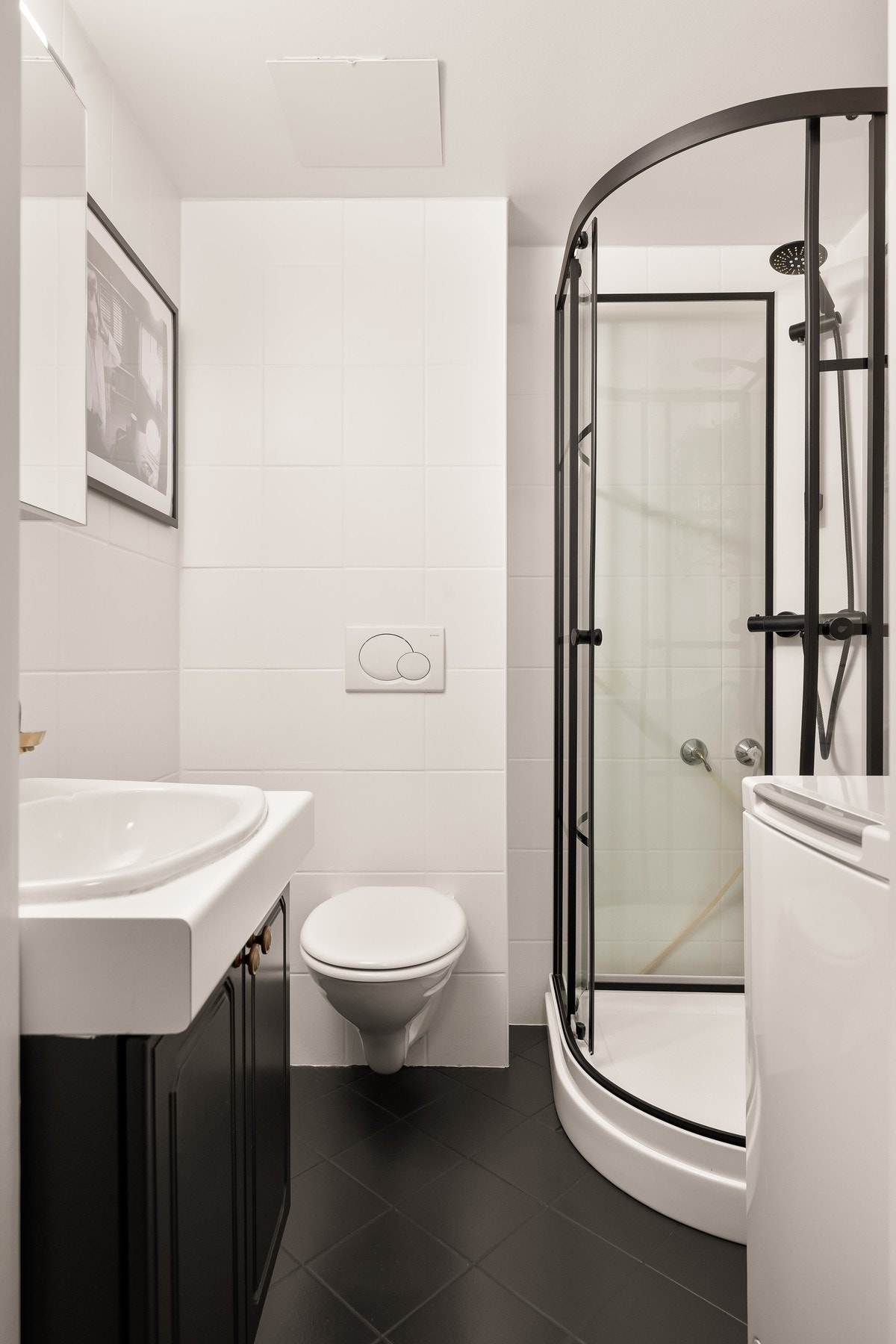 Badet fremstår tidløst med flislagte overflater, varme i gulv og opplegg for vaskemaskin. Galleribilde