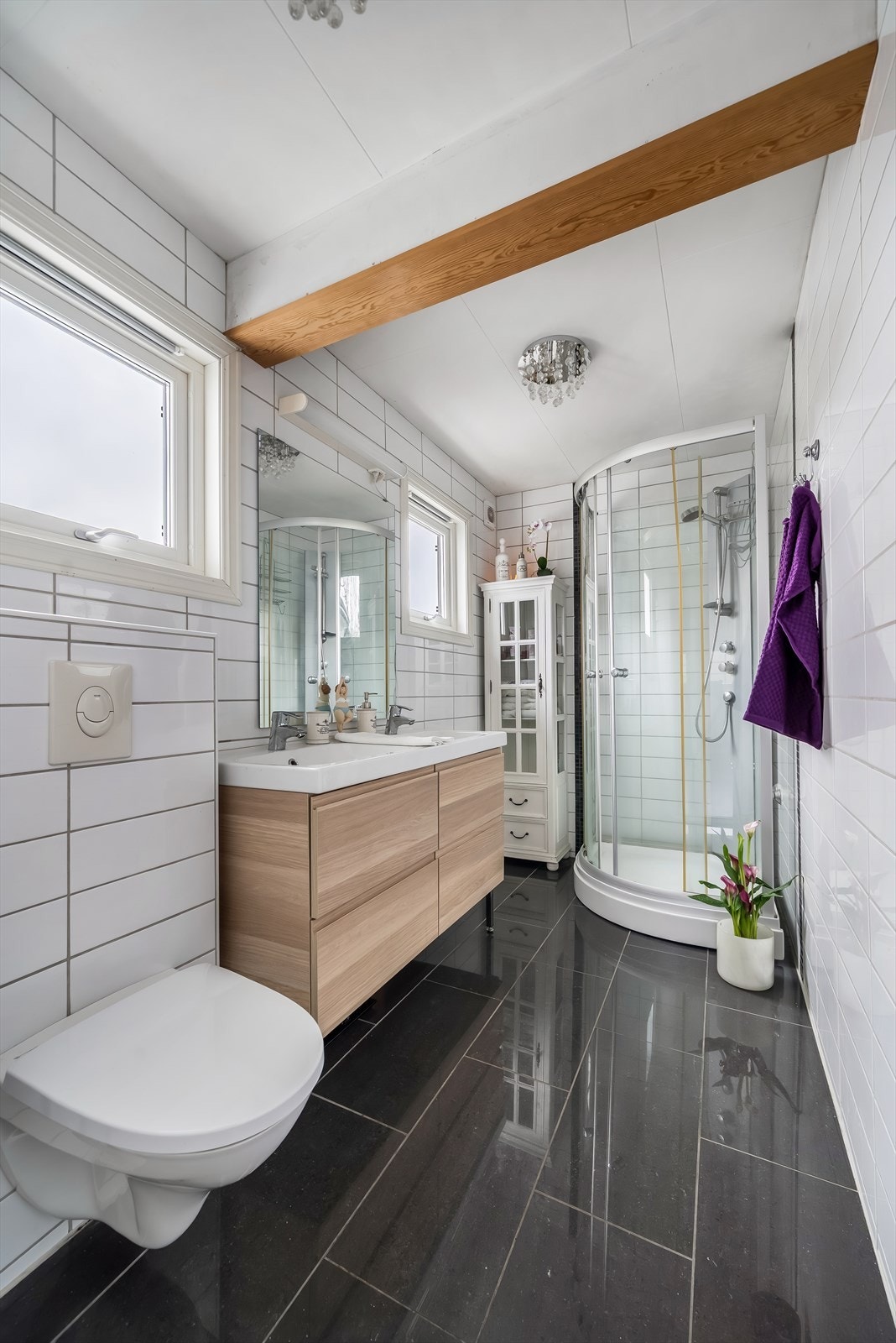 Bad i 1.etasje med moderne baderomsinnredning, vegghengt toalett og dusjkabinett. Fliselagte gulv med varmekabler og fliselagte vegger. Galleribilde