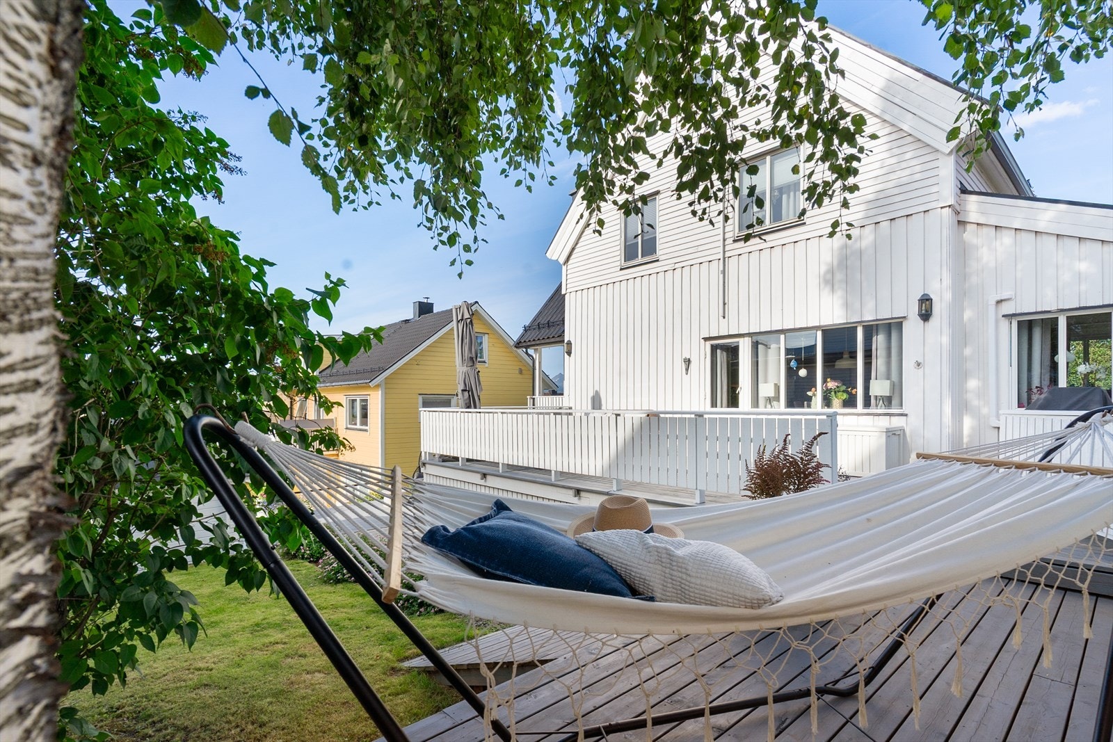 Fra hengekøyen får du et koselig blikk opp mot huset og terrassen - et uterom som binder hele eiendommen sammen Galleribilde