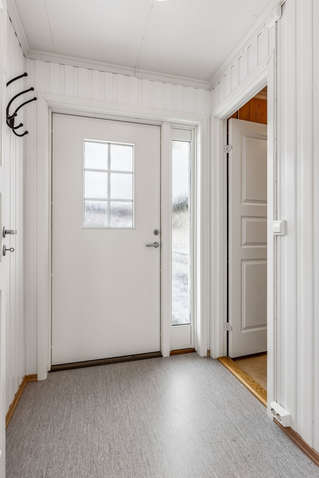 Inngangsdøren i tre med innfelt glass og sidefelt slipper lyset inn i entreen. Galleribilde