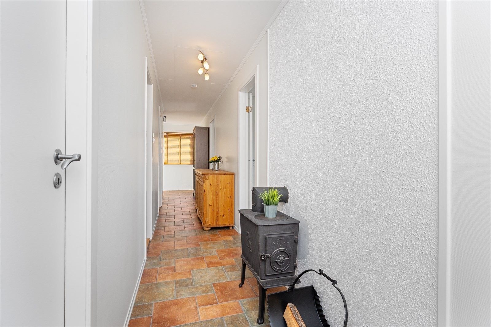I mellomgangen er det fliser på gulvet med varmekabler. Det er også en vedovn som blir benyttet på de kaldeste dagene. Videre inn finnes det ekstra lagringsplass i boder. Galleribilde