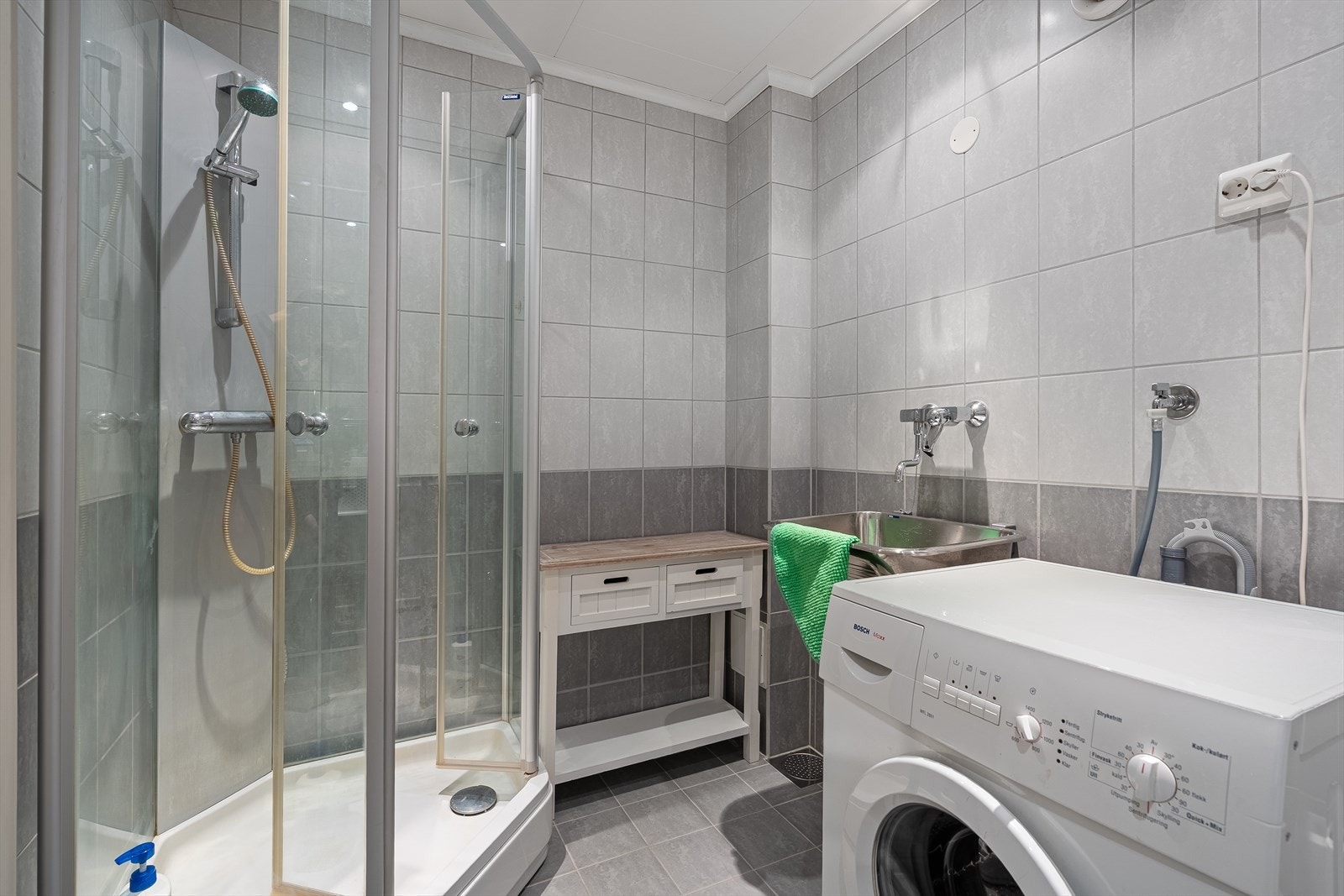Vegg i vegg med badet finner du vaskerommet hvor det er en praktisk utslagsvask, opplegg for vaskemaskin/tørketrommel, samt et dusjkabinett. Galleribilde