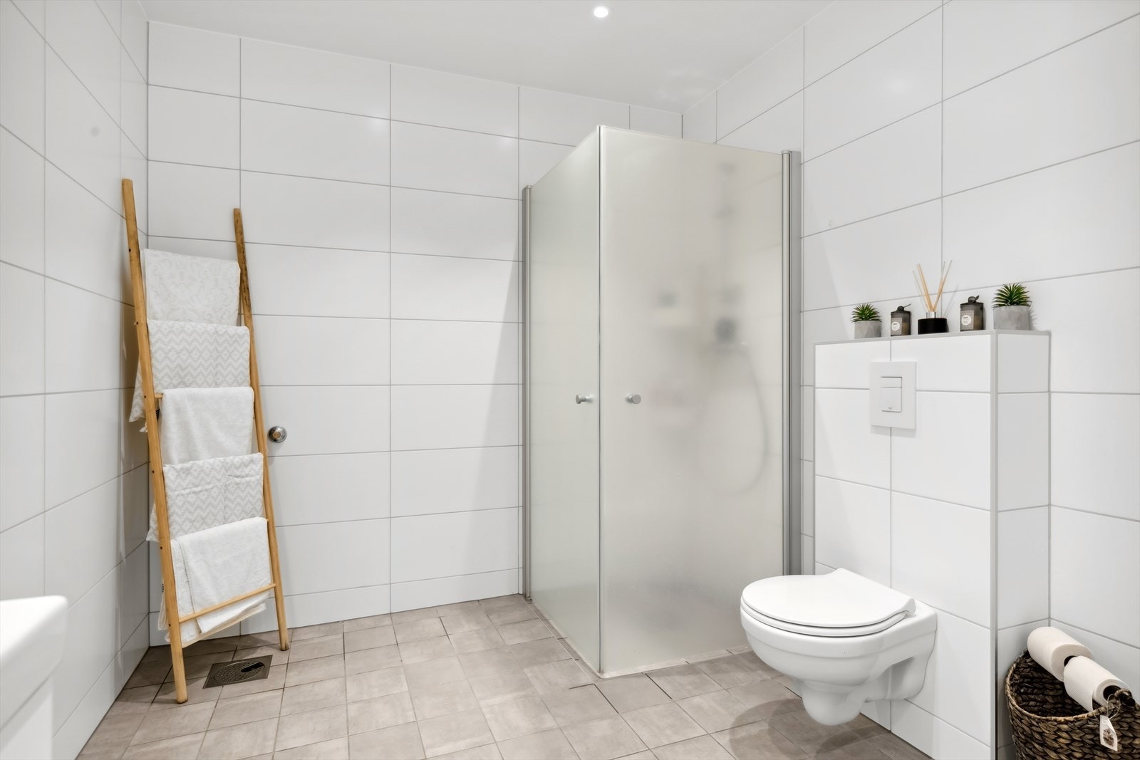 Badet har åpen dusjløsning, vegghengt toalett og stilrene fliser. Galleribilde