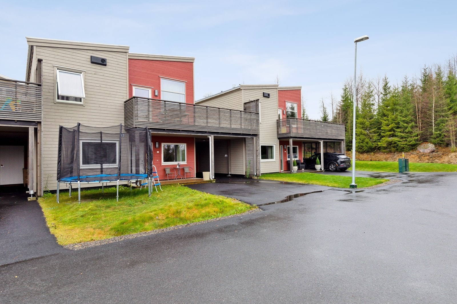 Stilren enebolig fra 2020 med trepanel og carport, omgitt av grønne omgivelser. Galleribilde