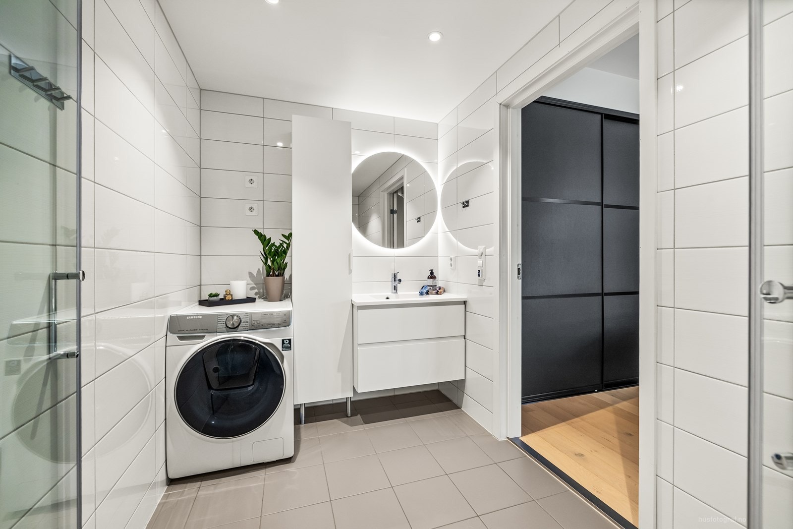 Badet er stilrent innredet med lyse fliser og varmekabler i gulv. Det er opplegg for vaskemaskin. Galleribilde