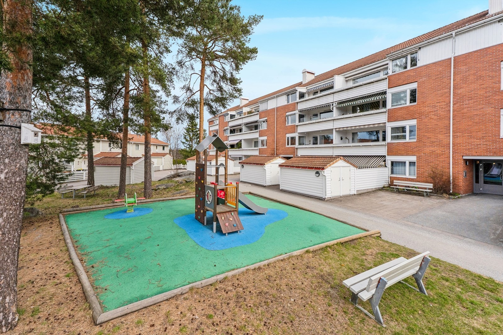 Store fellesareal opparbeidet med asfalterte adkomstveier/plasser, gressplen, beplantning, trær, lekeapparater m.m. Galleribilde