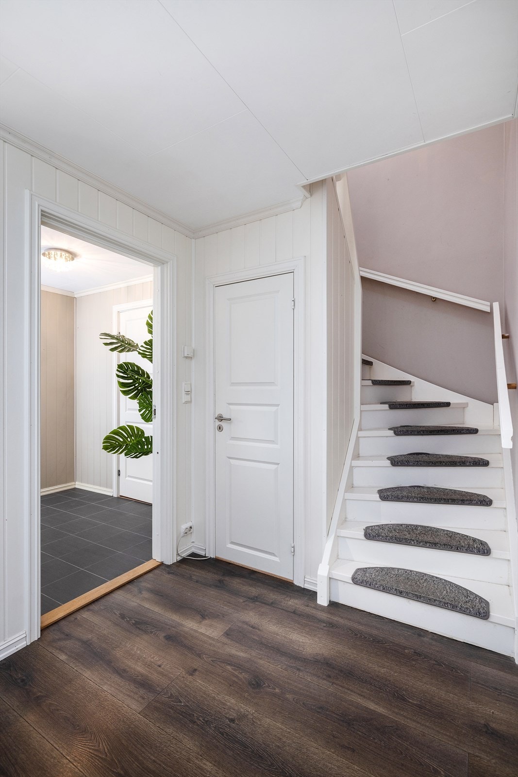 Malt tretrapp med teppe på trinnene leder opp til andre etasje. Galleribilde