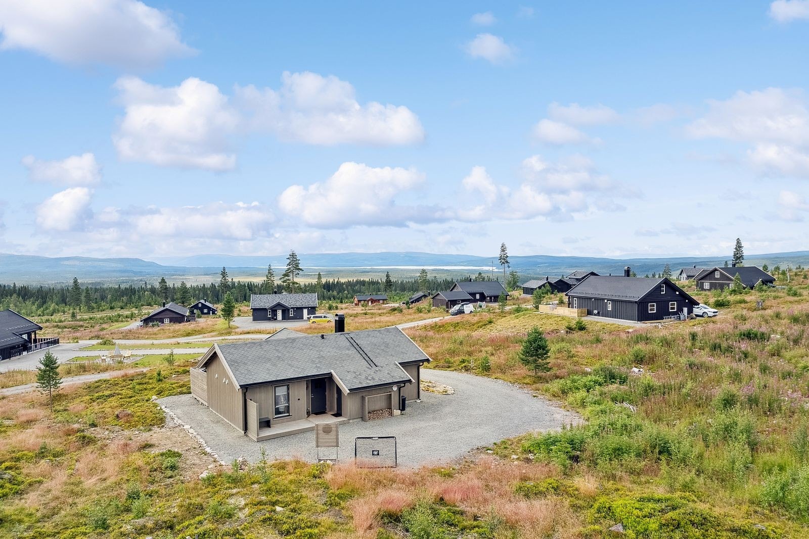 Hytta ligger på en svært romslig tomt på nærmere 2 mål, omgitt av ekte naturtomt med lyng, skogsbunn og vakre furutrær som rammer inn eiendommen. Den singelbelagte innkjøringen leder inn til en stor gårdsplass med god plass til flere biler. Galleribilde