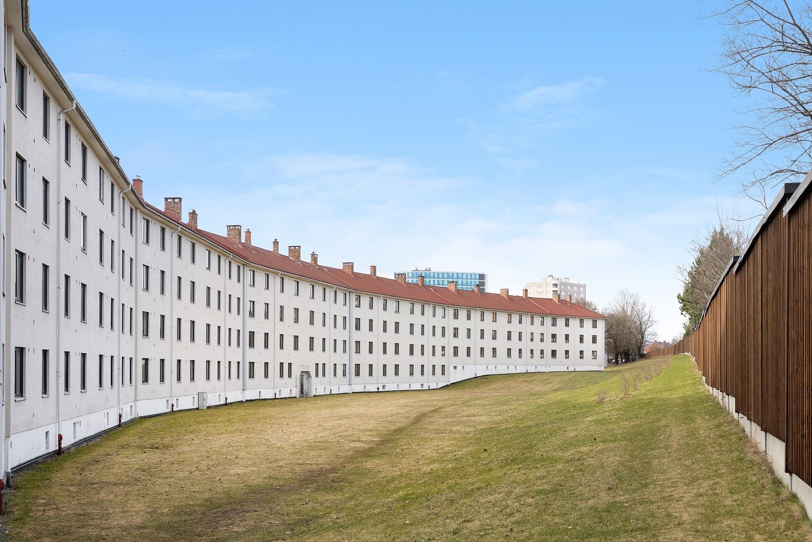 Langstrakt bygningsmasse med grøntareal langs fasaden Galleribilde