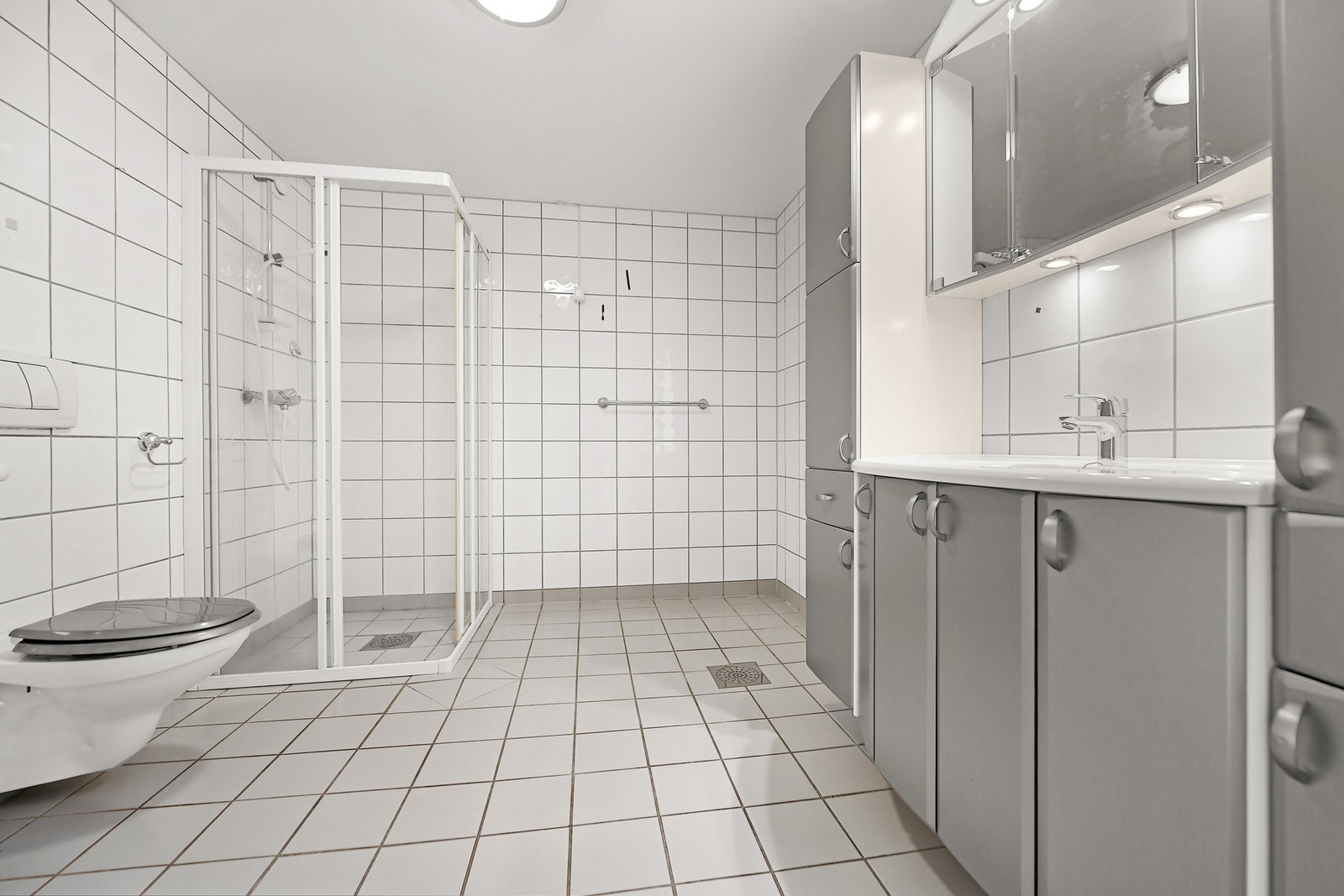 Badet er fra byggeåret. Gulvet er belagt med fliser og har vannbåren gulvvarme som gir behagelig, barfotvennlig varme. Badet er innredet med dusjhjørne, vegghengt wc, servantskap, sideskap, speilskap, elektrisk håndkletørker og opplegg for vaskemaskin. Galleribilde